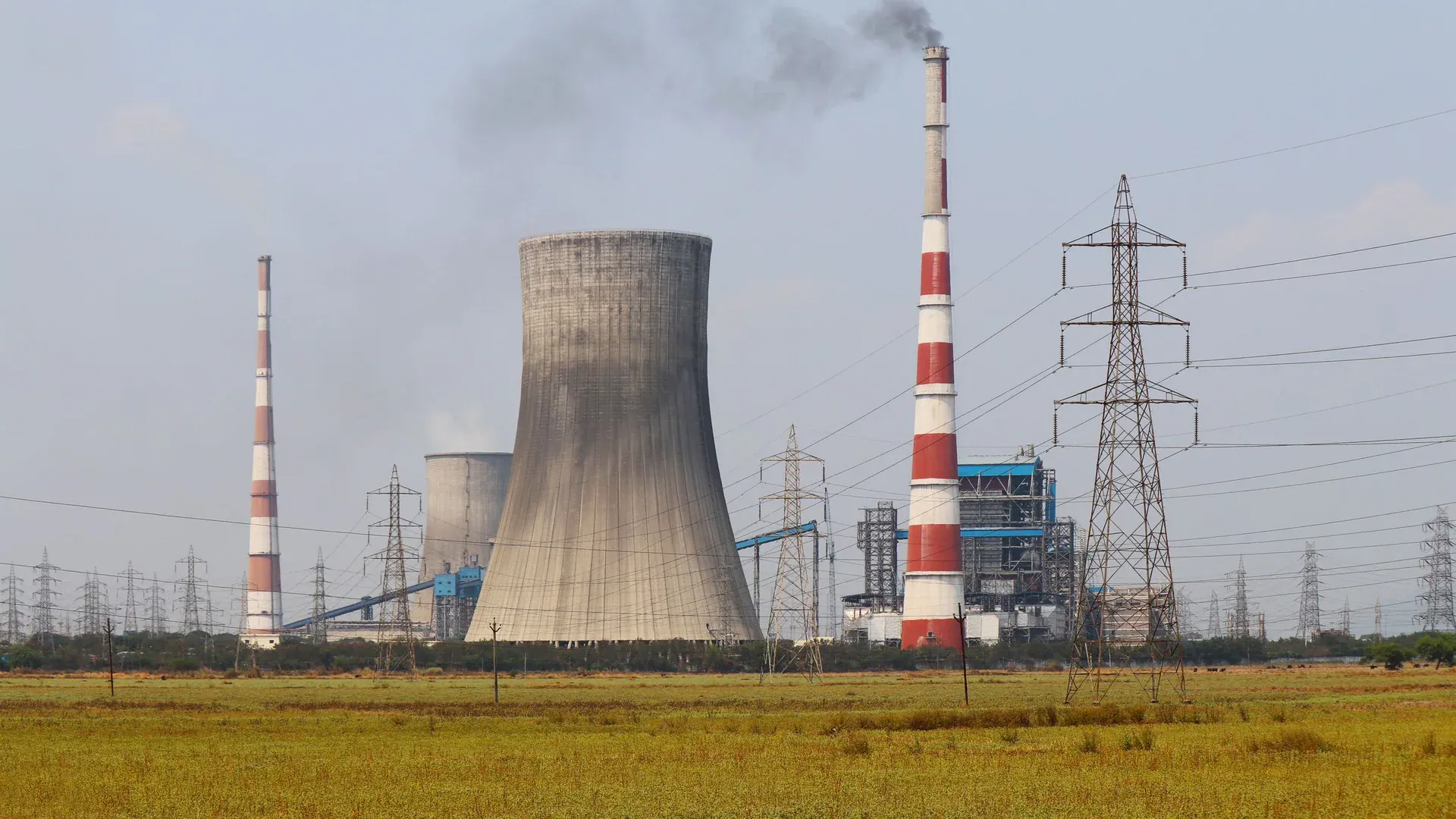 Smokestacks and a cooling tower emit smoke at a power plant in Vijayawada, India