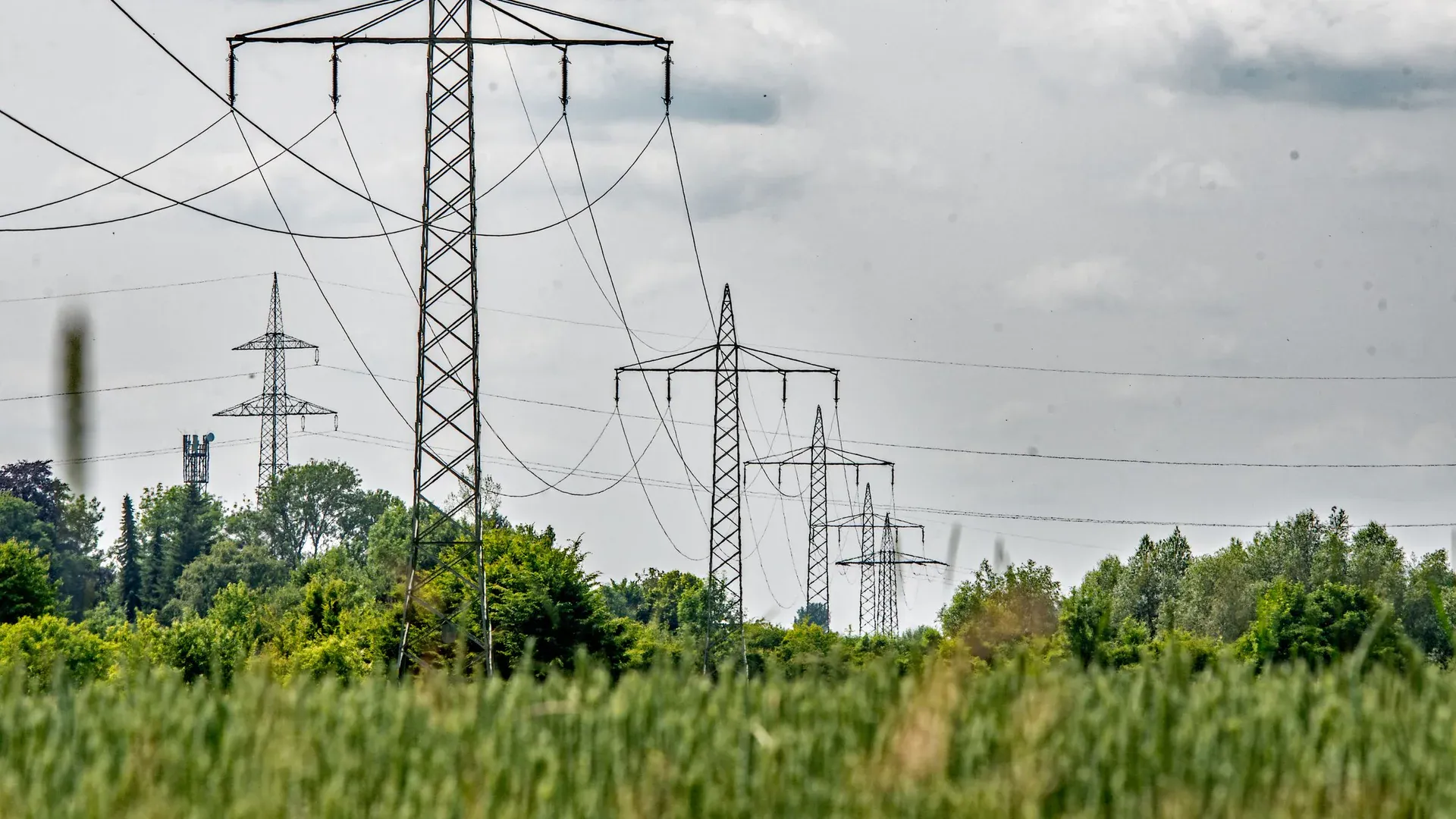 Transmission towers stretch across a lush field in Ingolstadt, Bavaria, Germany