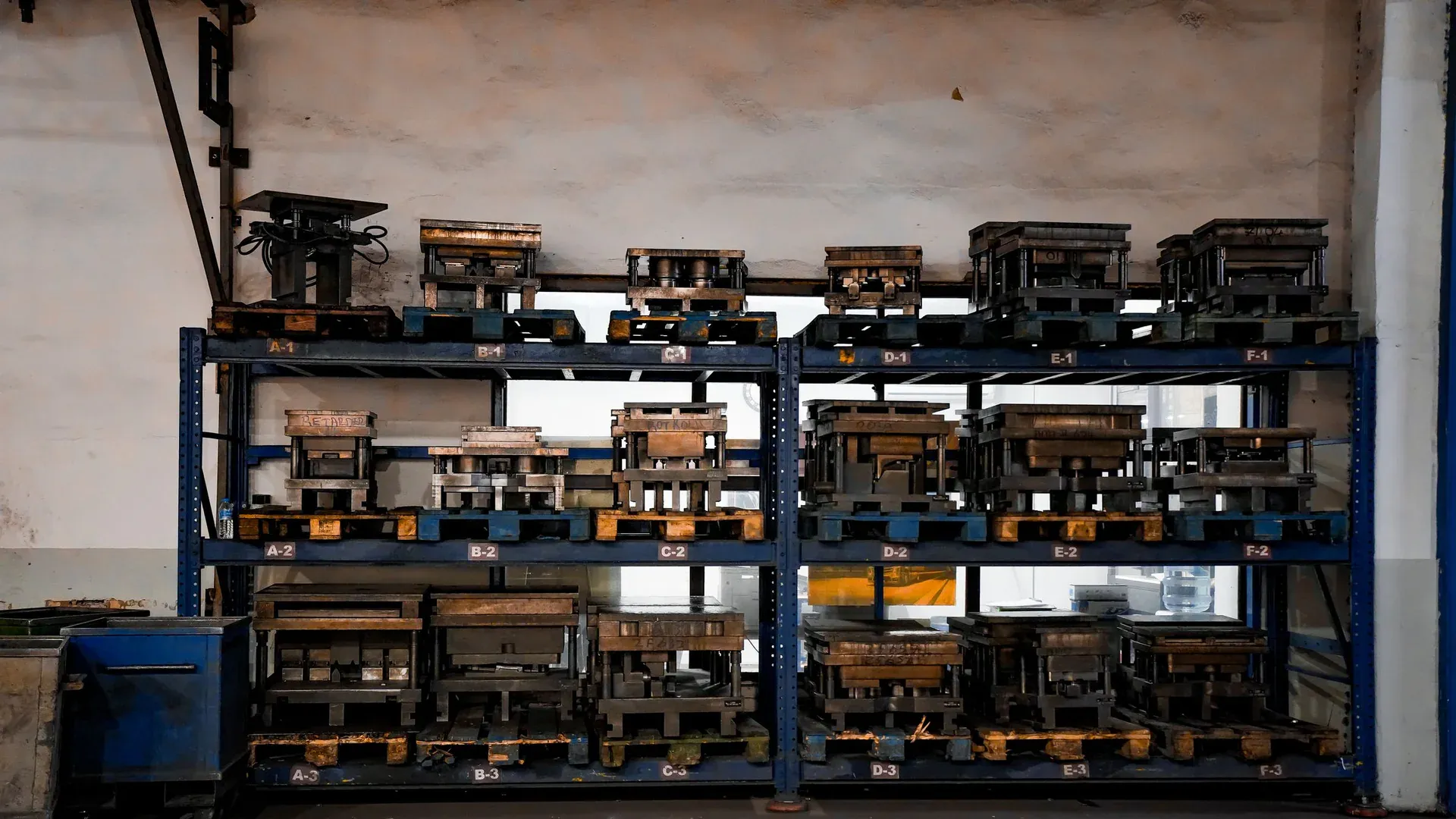 Industrial metal molds organized on numbered warehouse shelving