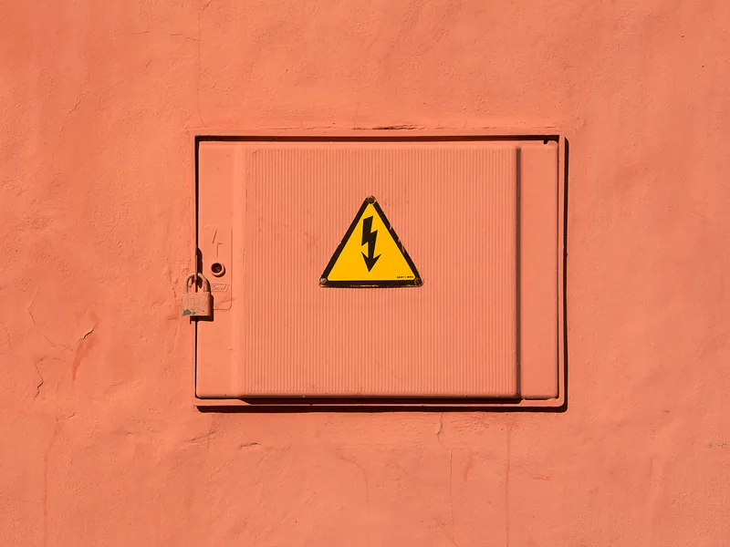Bright yellow high voltage warning sign on a locked electrical box