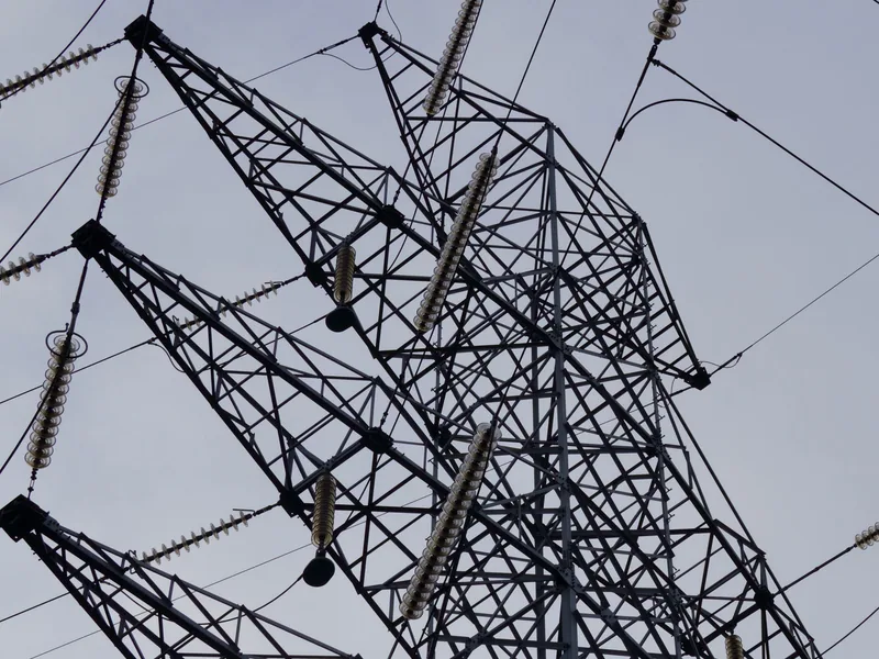 Low angle shot of a metal power transmission tower with cables against a clear sky
