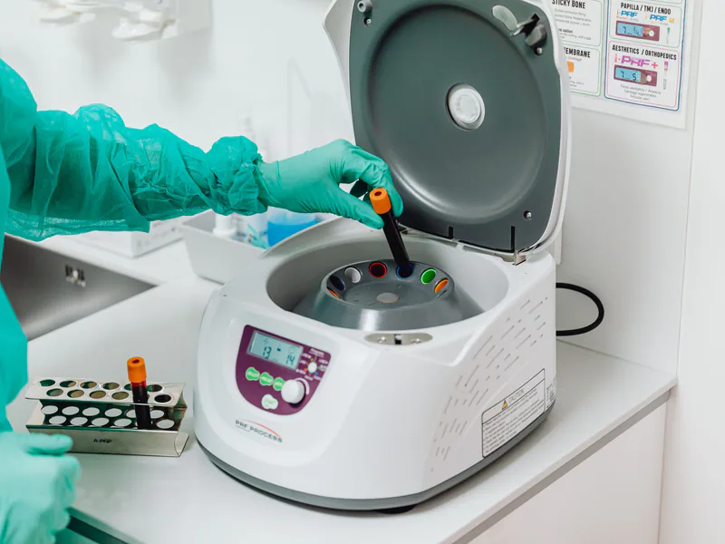A healthcare professional operates a centrifuge machine in a laboratory, ensuring sterile medical procedures