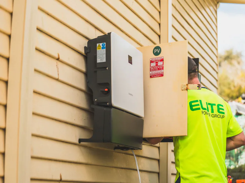 Electrician from Elite Power Group installing a solar inverter outside