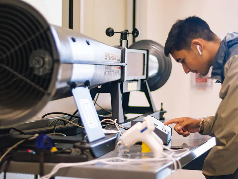 Young student interacts with jetstream apparatus in an engineering lab