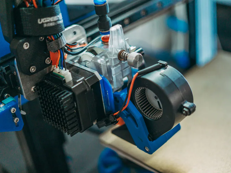 Detailed view of 3D printer parts showing wires and equipment in a workshop setting