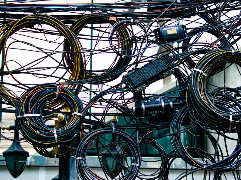 Intricate network of tangled power and communication cables outdoors