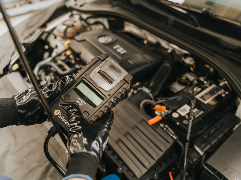Mechanic diagnosing a car engine with a diagnostic tool, showcasing technical expertise and automotive care