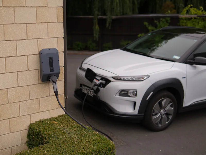 A white electric car charging at a station in Christchurch, New Zealand, showcasing modern eco-friendly transportation