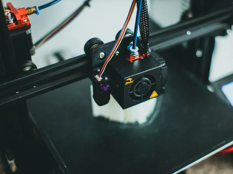 Detailed shot of a 3D printer creating an object, focusing on the cooling fan and print head