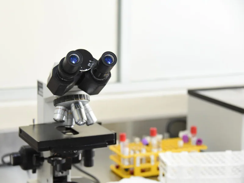 A close-up of a laboratory microscope with test tubes in a scientific research facility