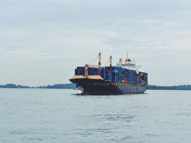 Large cargo ship transporting containers across a calm sea, symbolizing global logistics