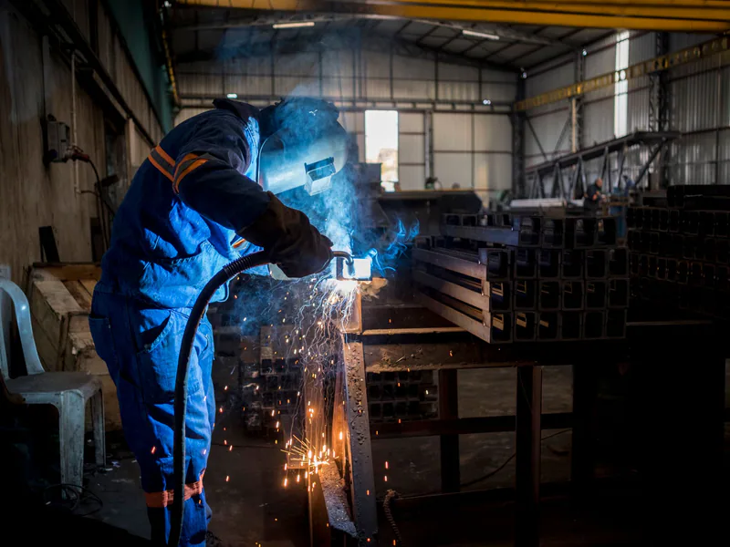 A welder at work inside a manufacturing facility in Adana, Türkiye. Sparks fly during the process