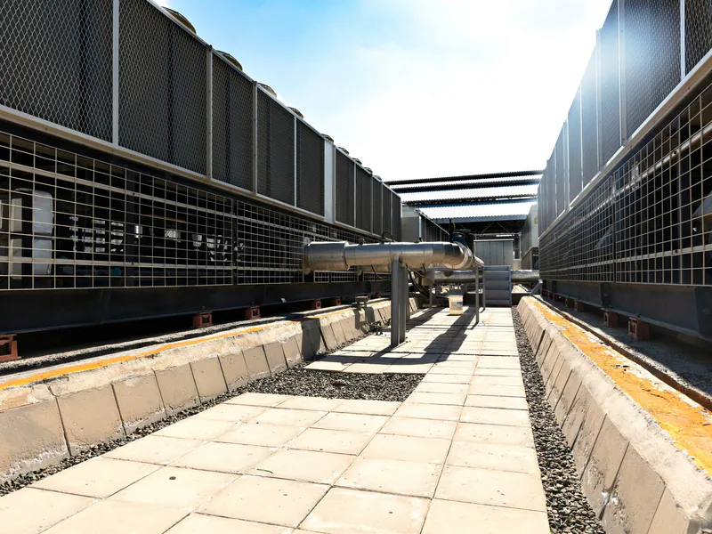View of a large industrial cooling system with metal pipes and grids outdoors under bright daylight
