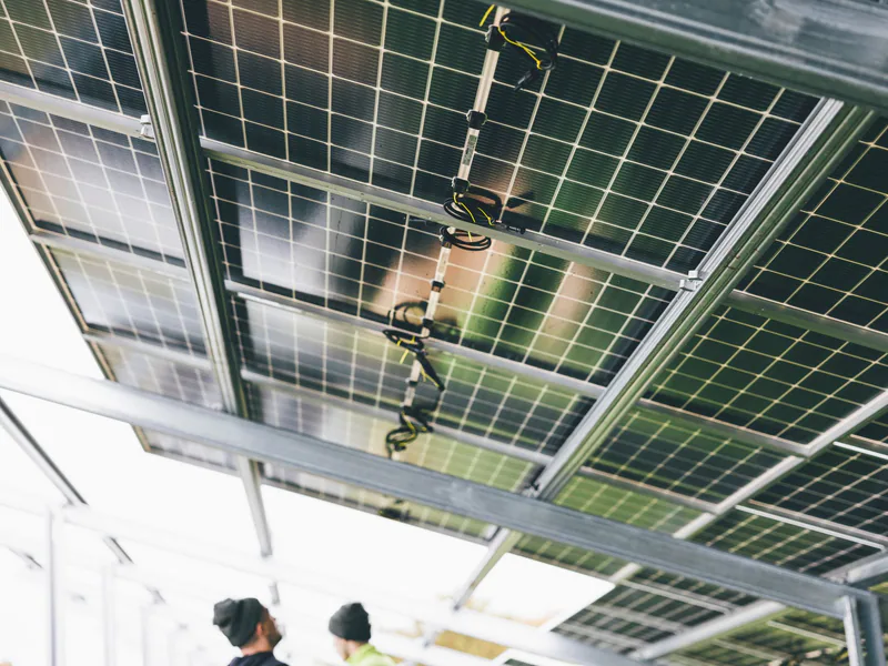 Close-up of solar panels being installed outdoors with technicians visible