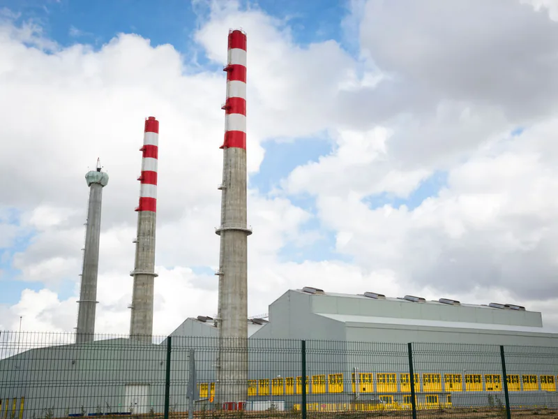 Factory chimneys against a blue sky symbolize industrial power and environmental impact