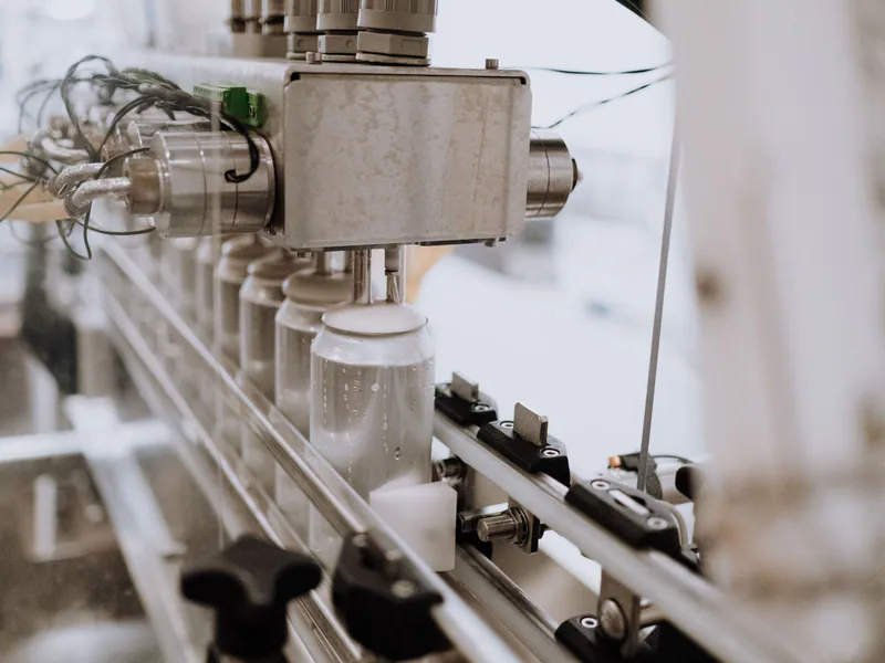 Close-up of an automated can filling machine in a beverage production line