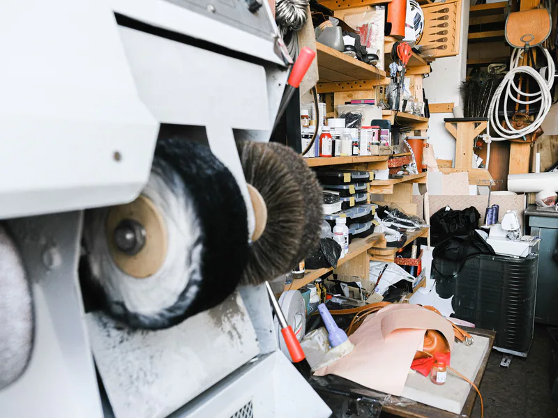 Busy workshop interior featuring a shoe polishing machine and various tools and supplies
