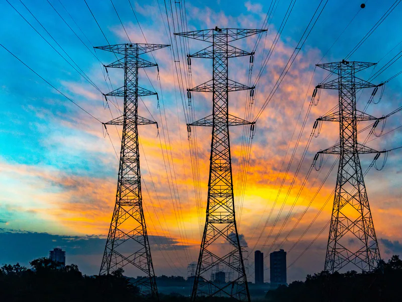 High voltage power lines against a dramatic sunset sky, symbolizing energy and technology