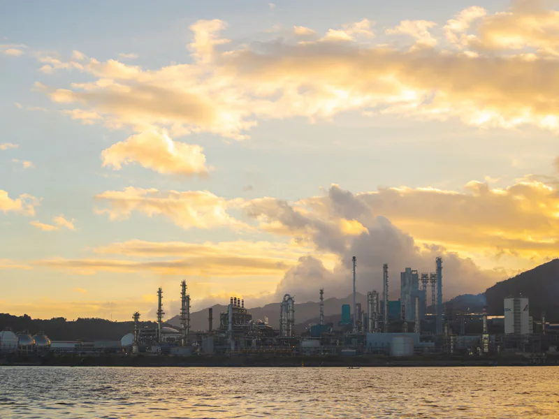 A stunning view of industrial chimneys and skyline with smoke at sunset over the water