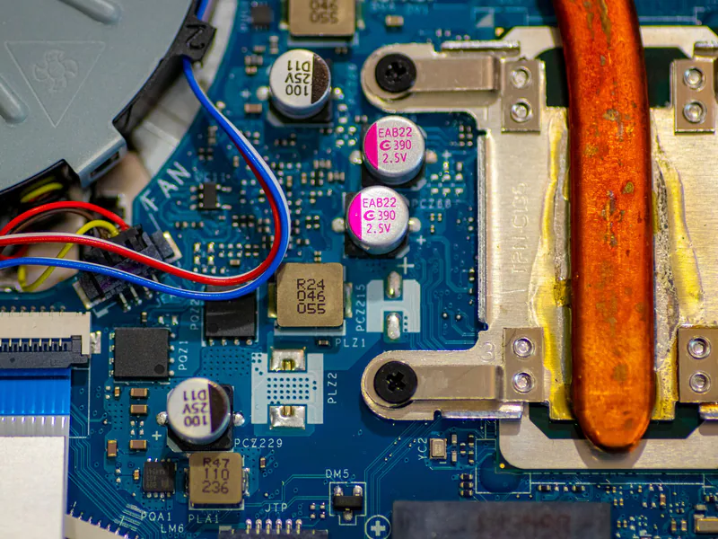 Detailed image showing circuitry and components on a computer motherboard with wires and capacitors