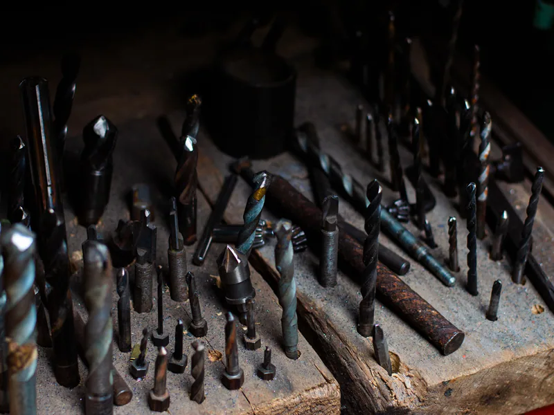 Collection of various drill bits on a wooden board, ideal for metalwork and woodworking