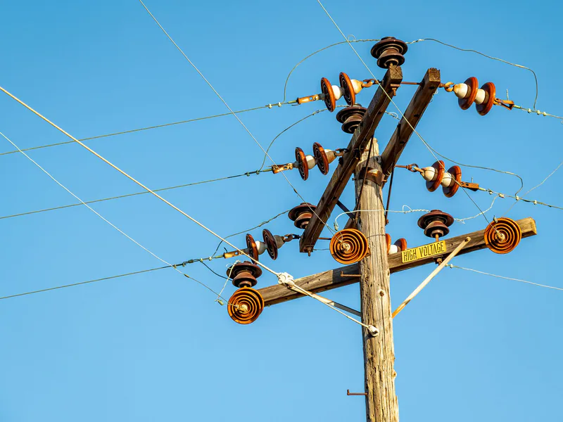 High voltage power line and insulators captured against a clear blue sky