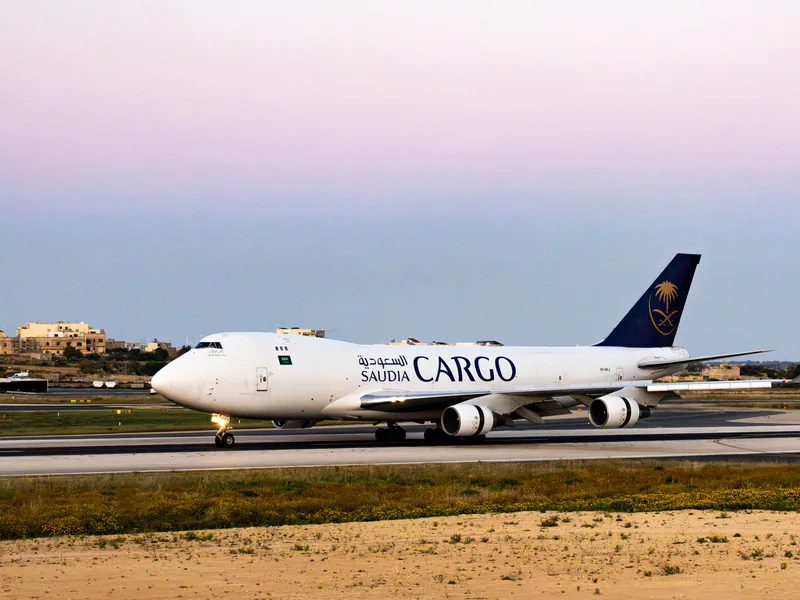 A Saudia Cargo plane on a runway at twilight with a serene sky background