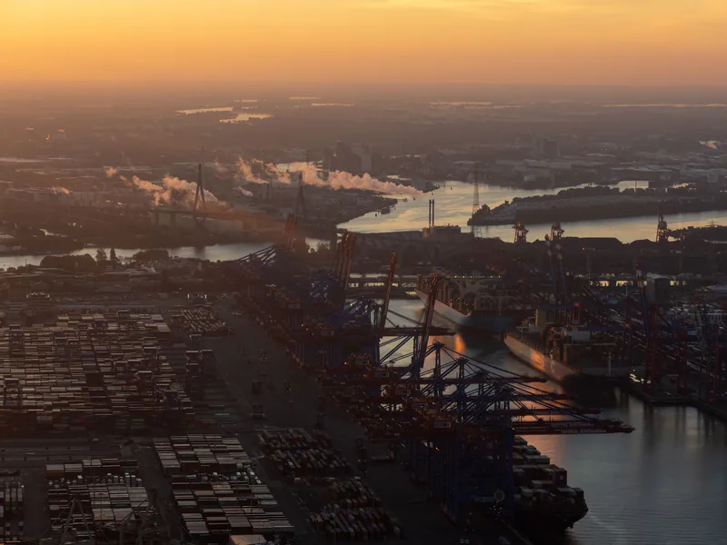 Stunning aerial view of Hamburg’s bustling port during sunrise, showcasing cranes and container ships