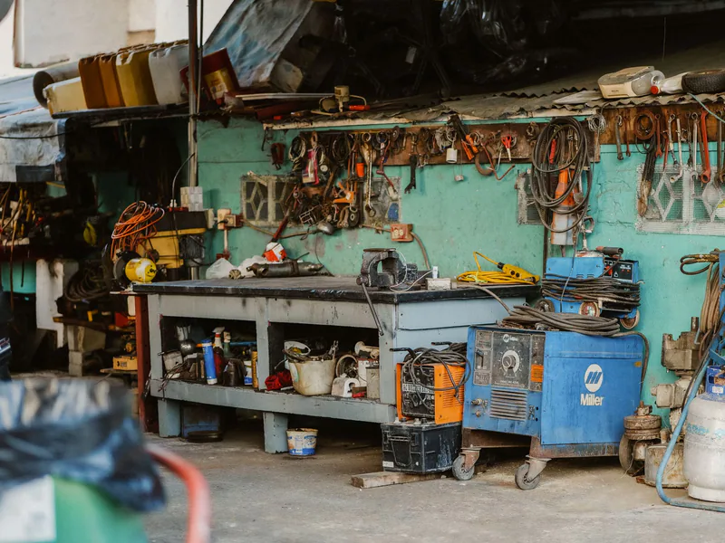 A cluttered workshop with tools, welding equipment, and storage solutions