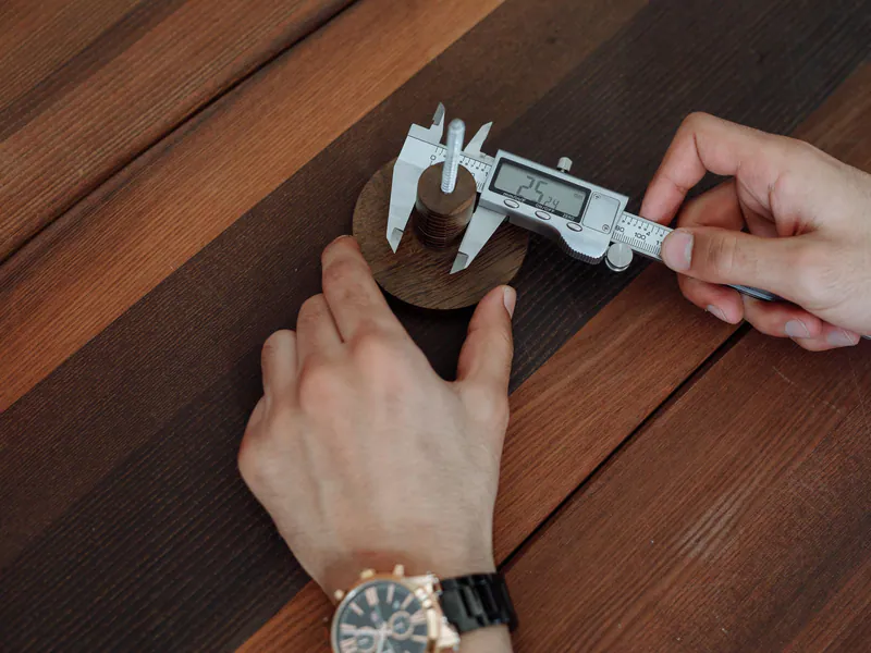 Inspector measuring a small metal part with a digital caliper