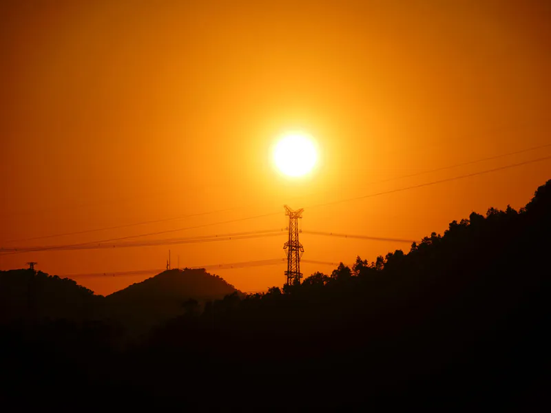 Transmission tower silhouetted by the setting sun