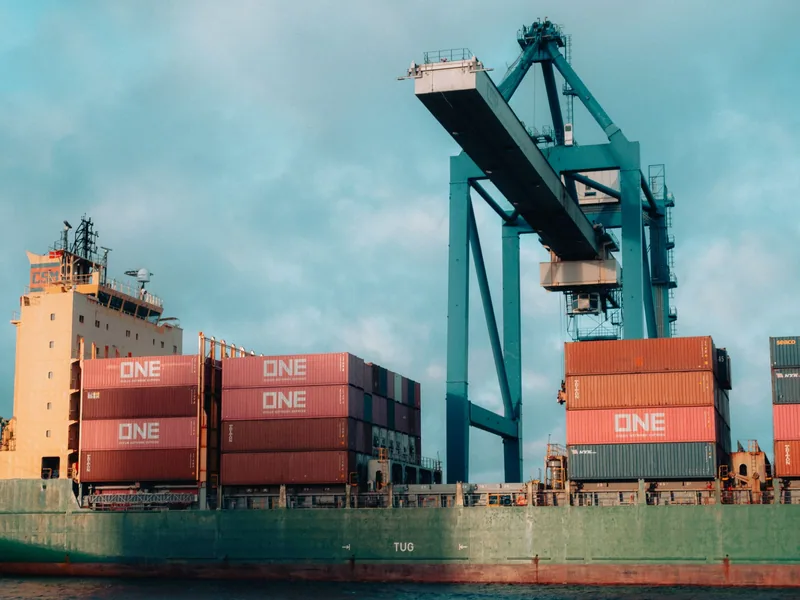 Container ship carrying freight beneath port cranes