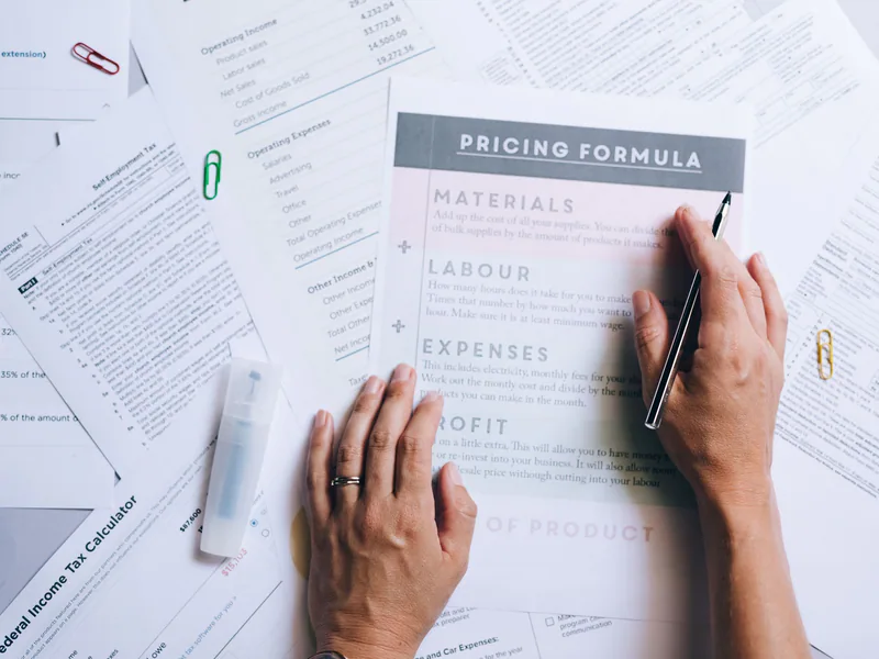 Hands reviewing manufacturing cost and pricing worksheets